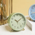 Green alarm clock on a white surface with a beige wall in the background