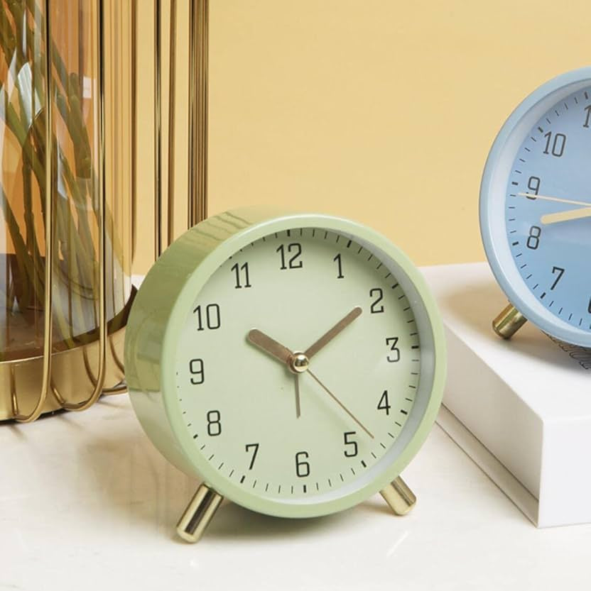 Green alarm clock on a white surface with a beige wall in the background