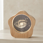 A star-shaped wooden night light with a glowing galaxy design on the front, set on a light beige surface against a neutral background.