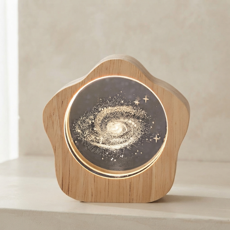 A star-shaped wooden night light with a glowing galaxy design on the front, set on a light beige surface against a neutral background.