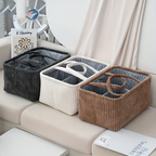 Three corduroy storage baskets in black, white, and brown on a couch.