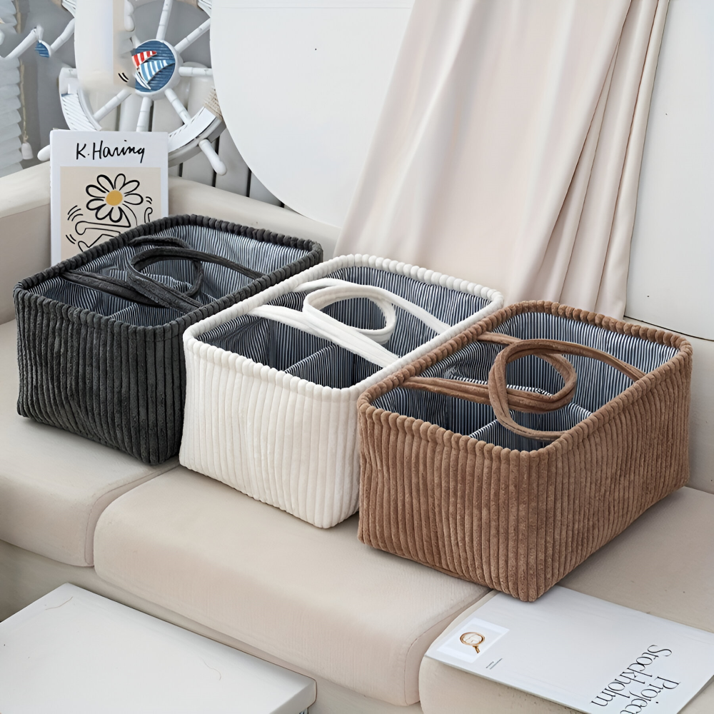 Three corduroy storage baskets in black, white, and brown on a couch.