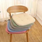 Stack of colorful seat cushions on a wooden chair with a neutral background