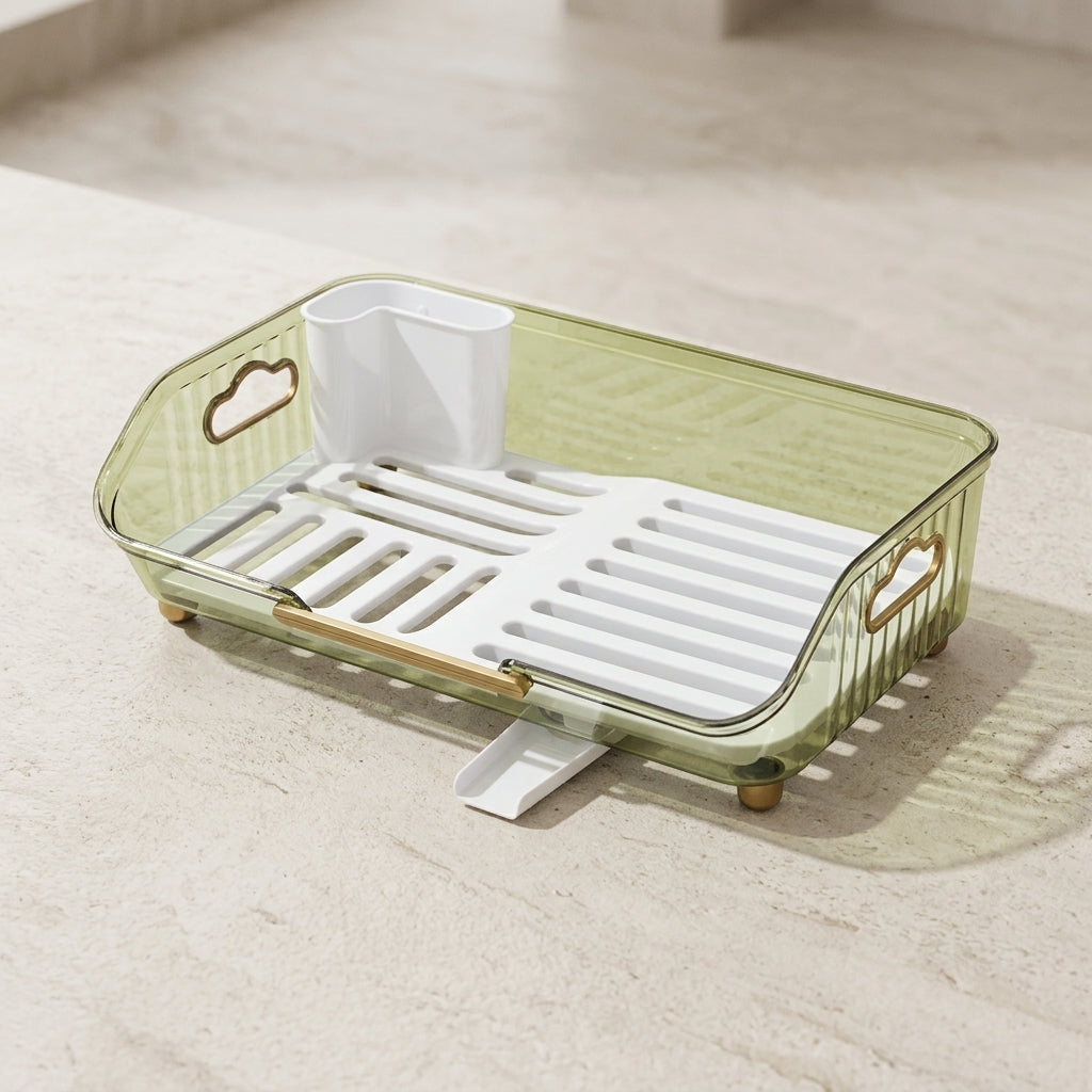 A translucent sage green plastic dish rack with a white slotted tray, a white cup holder, and gold-toned hardware, shown on a light beige stone surface.