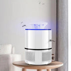 A white cylindrical mosquito trap device with a glowing blue light at the top, displayed on a wooden table in a modern living room setting.