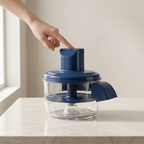 Blue kitchen appliance on a white countertop with a hand pointing at it.