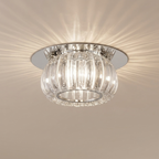 A modern semi-flush mount ceiling light fixture with a clear ribbed glass shade and a polished silver/chrome metal base, shown illuminated against a beige ceiling.
