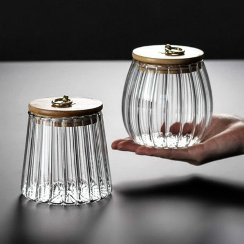 Two glass jars with wooden lids on a reflective surface