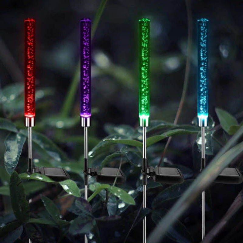 Four colorful LED lights on stakes with a blurred natural background