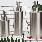Three metallic soap dispensers on a checkered background with leaves.