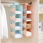 Two hanging shelves in pastel colors with folded clothes inside, mounted on a closet rod.