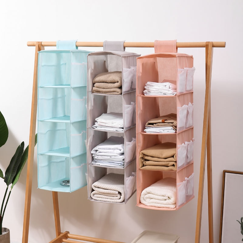 Hanging shelf organizer with multiple compartments on a wooden stand against a white wall.