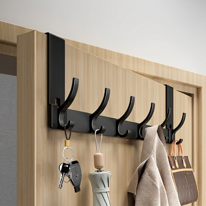 Black wall-mounted hook rack with keys, umbrella, and bag on a wooden door.