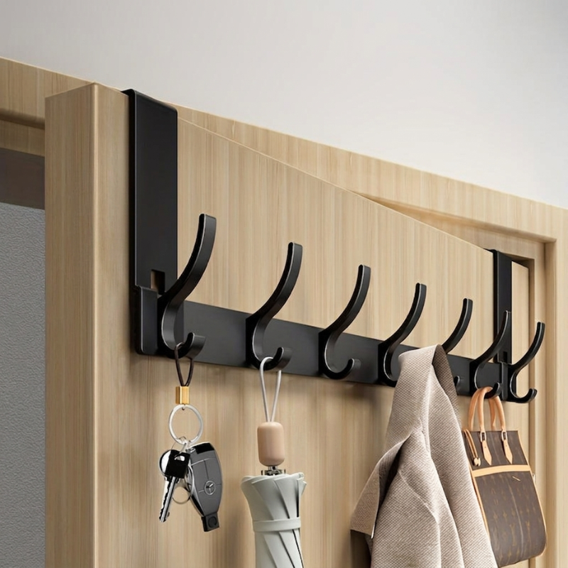 Black wall-mounted hook rack with keys, an umbrella, and a coat on a wooden door.
