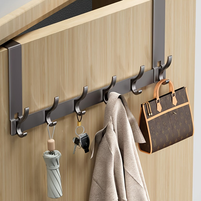 Wall-mounted hook rack with various items hanging on it against a wooden background