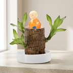 Decorative item with a small figurine on a wooden stump surrounded by green leaves.