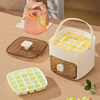 Ice cube tray with yellow cubes on a wooden table, next to a glass of pink lemonade.