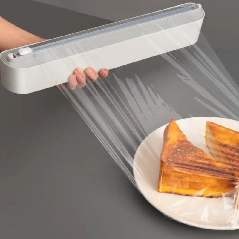 Hand using a plastic wrap dispenser to cover a plate of food on a gray background