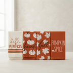 Four autumn-themed fabric towels or napkins displayed side by side on a light surface. The set includes designs with 'hello PUMPKIN', 'harvest fall', white pumpkins on an orange background, and 'PUMPKIN SPICE' text on an orange background.