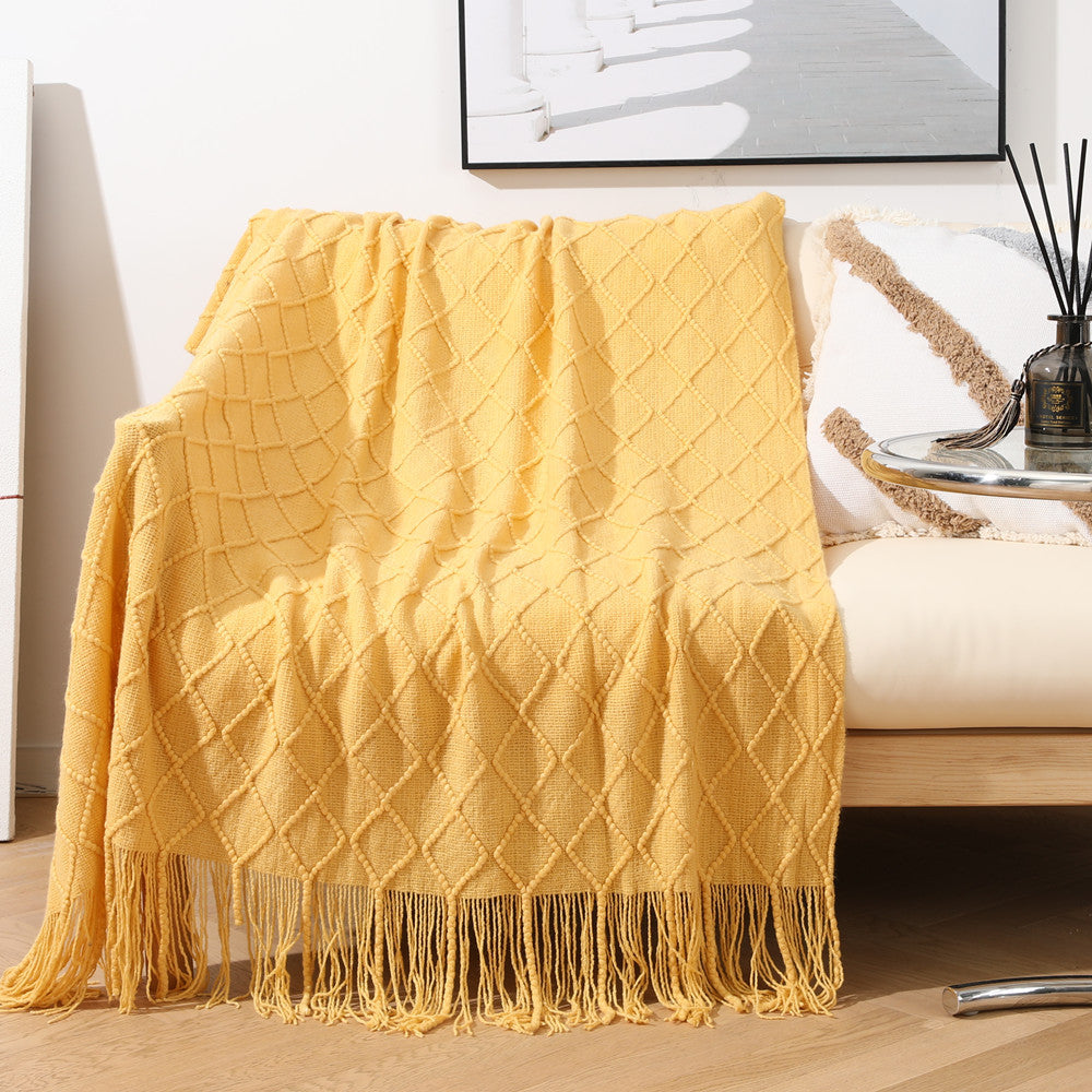 Yellow textured throw blanket with fringe draped over a chair in a living room setting.