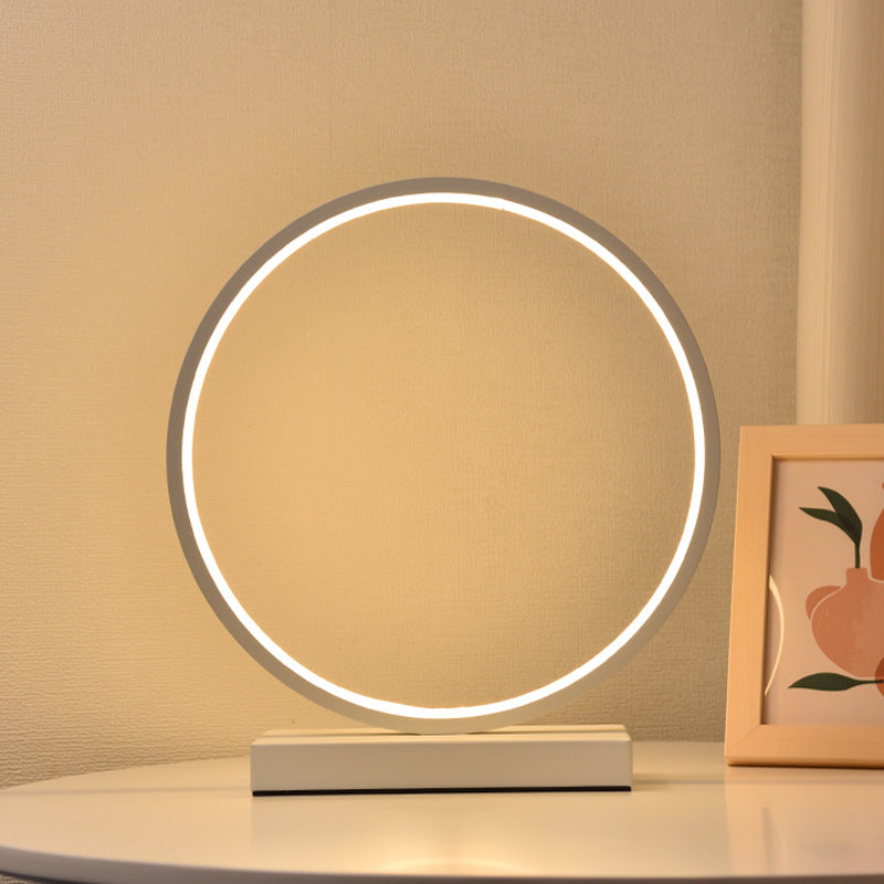 Round table lamp with circular LED light on a beige surface