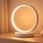 Round LED table lamp with a warm glow on a wooden surface.