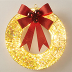 A circular holiday wreath light with warm white LED lights and a large red glitter bow on a light gray background.