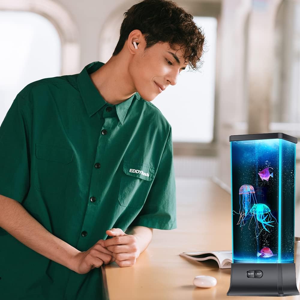 Person wearing a green shirt with a jellyfish aquarium on a table