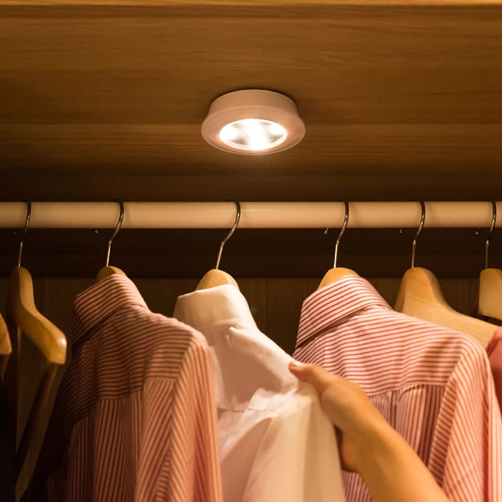 Clothing items on hangers under a light fixture in a closet.