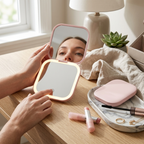 Person using a handheld mirror with LED lights on a table with makeup items.