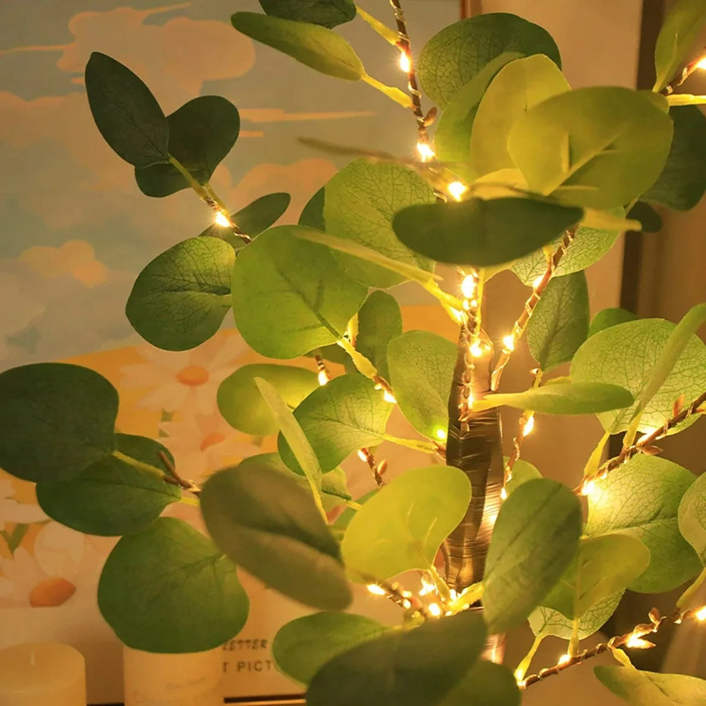 Artificial plant with string lights against a blurred background