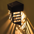 Solar-powered outdoor light fixture casting a warm glow on a wall.