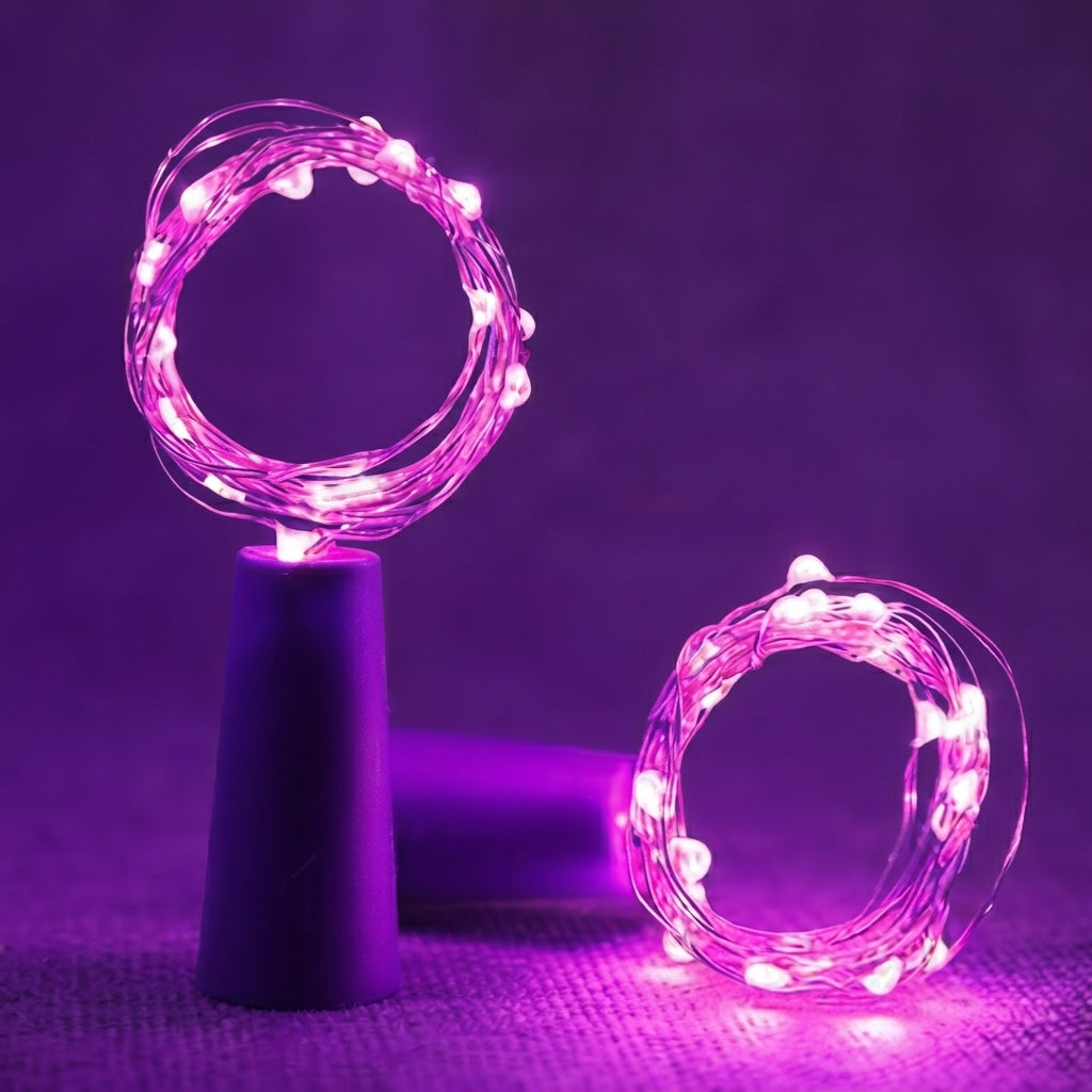 Twisted wire fairy string lights glowing in pink and purple, shown coiled on a dark stand and on the floor against a purple-lit background.
