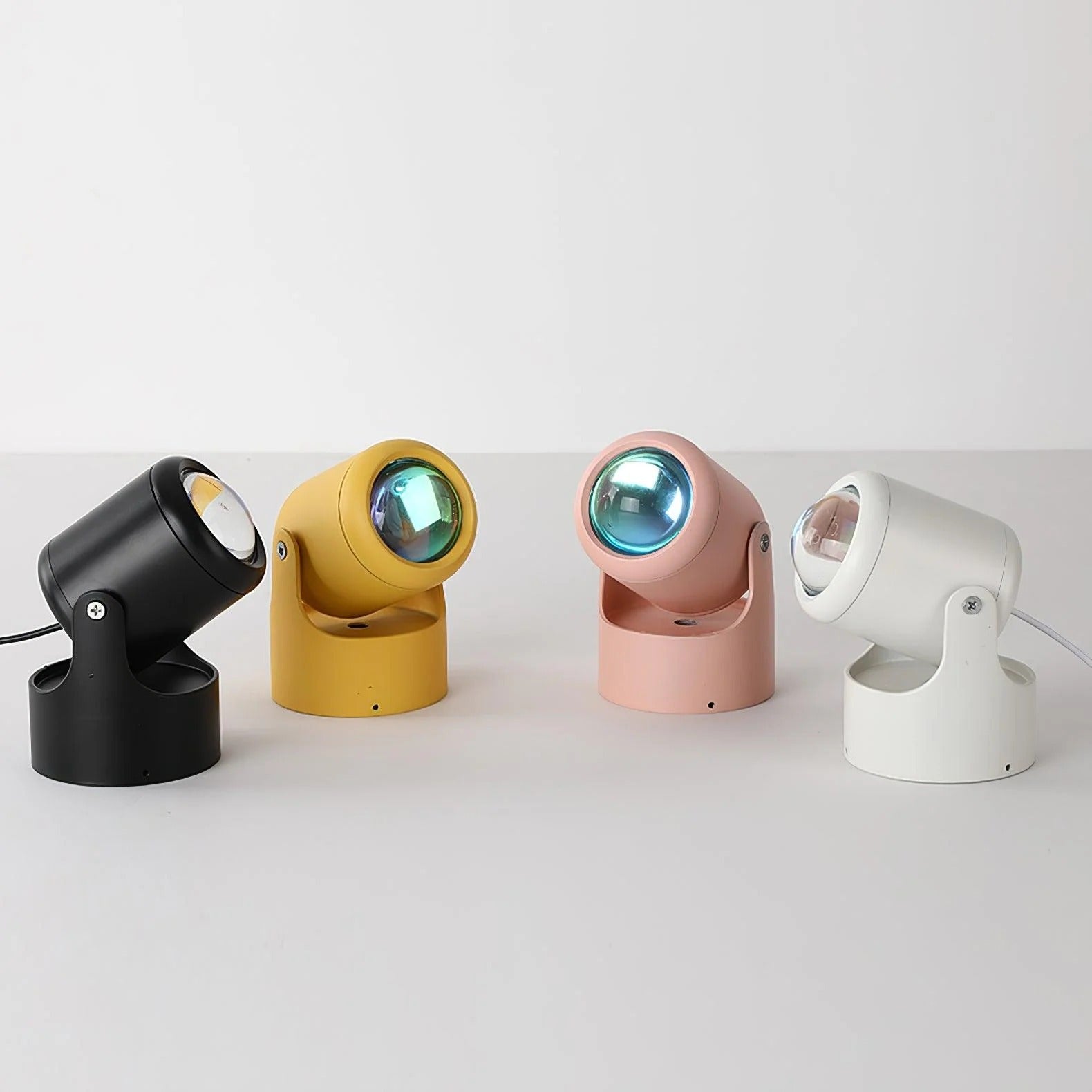 Four colorful mini spotlights on a white surface with a light gray background