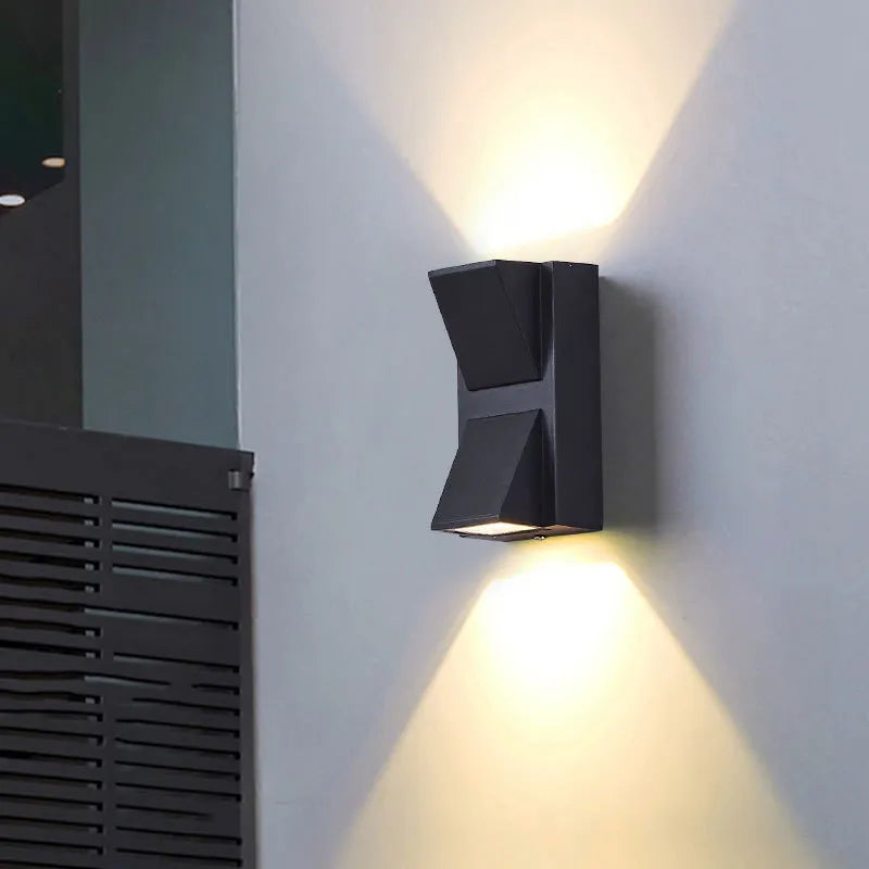 Modern black wall-mounted outdoor light fixture on a gray wall.