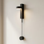 Modern black wall lamp with a cable extension on a light beige wall.