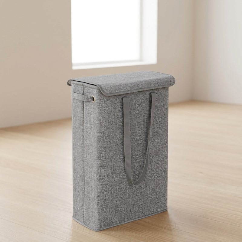 Gray laundry basket with a handle on a wooden floor.