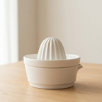 White ceramic citrus press on a wooden surface with a neutral background