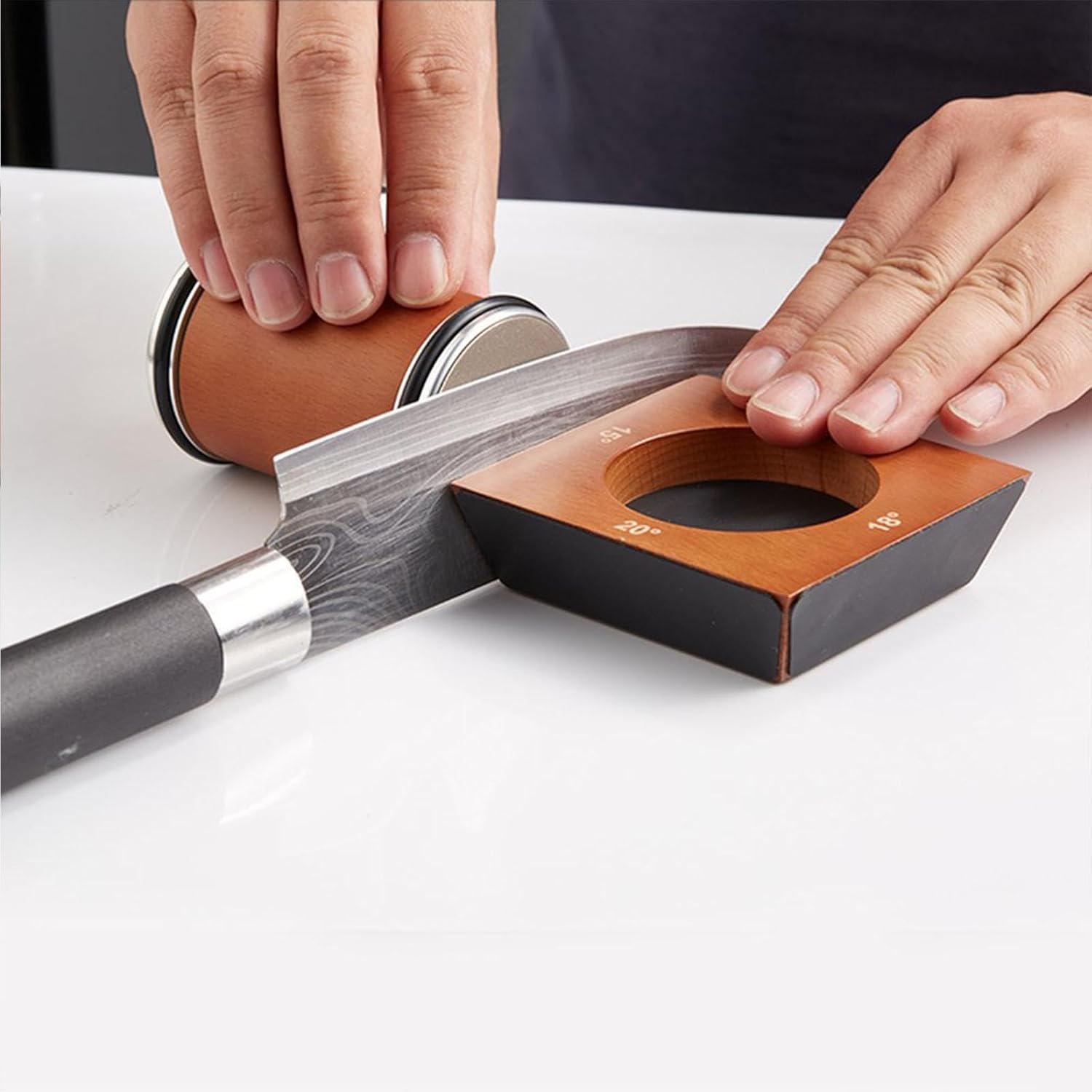 Knife being sharpened on a manual knife sharpener with hands holding it