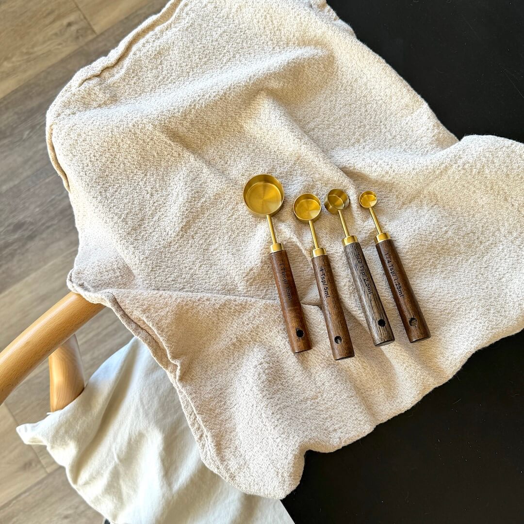 Set of five wooden spoons with gold ends on a white towel