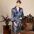 Man wearing a blue and white striped satin robe in a room with a floral arrangement and a brown couch.