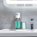 Bathroom setting with a soap dispenser, cups, and a faucet on a sink.
