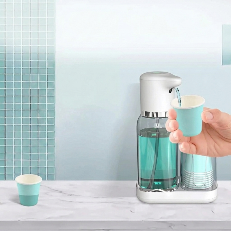Hand using a soap dispenser with small blue cups on a bathroom counter.