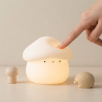 Mushroom-shaped night light with a hand touching it on a beige background
