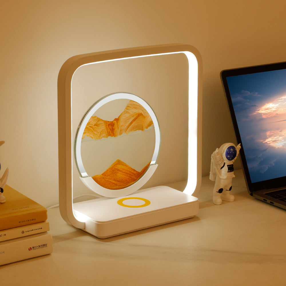 Modern desk lamp with a circular design on a desk next to a laptop and books.