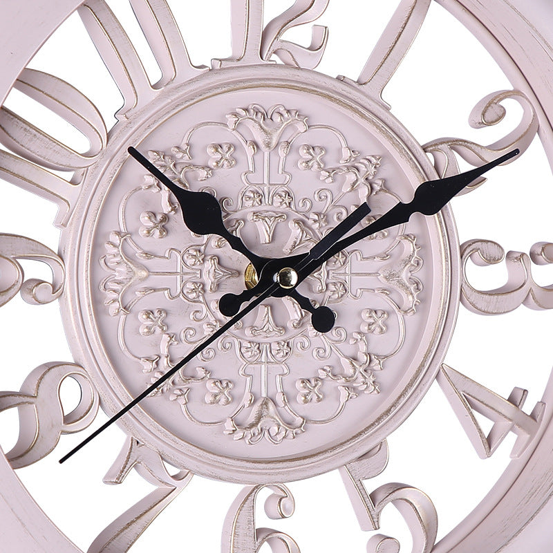 Decorative wall clock with intricate designs and black hands on a white background