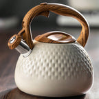 White ceramic teapot with wooden handle and lid knob on a dark surface