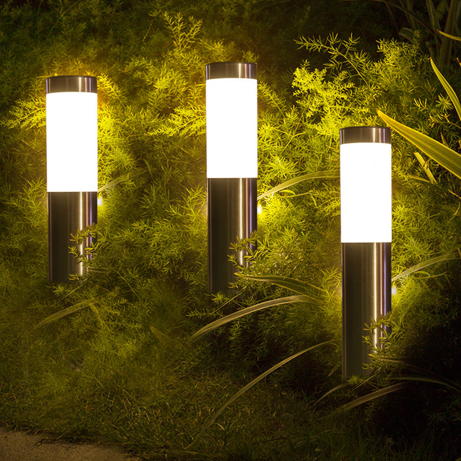 Three outdoor garden lights illuminating a green bush at night.