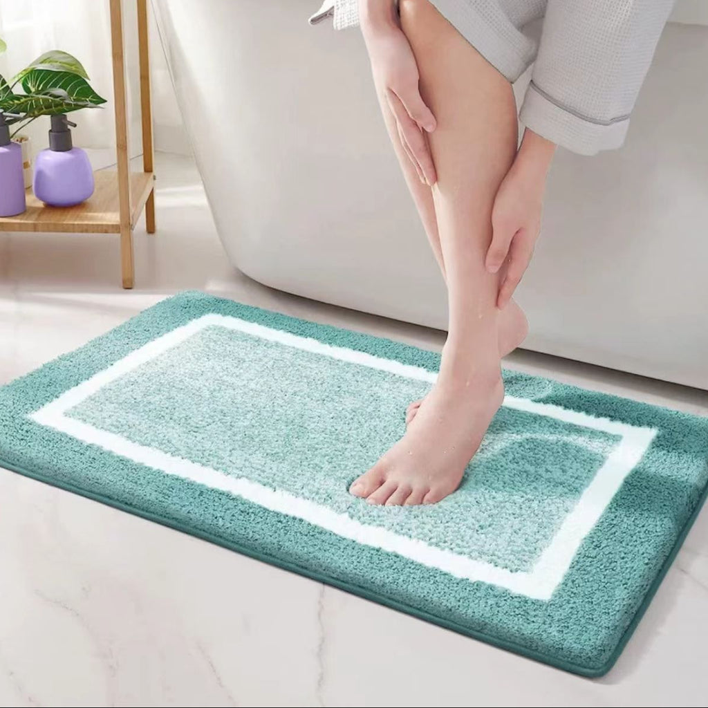 Person stepping onto a teal bath mat with white border in a home setting.