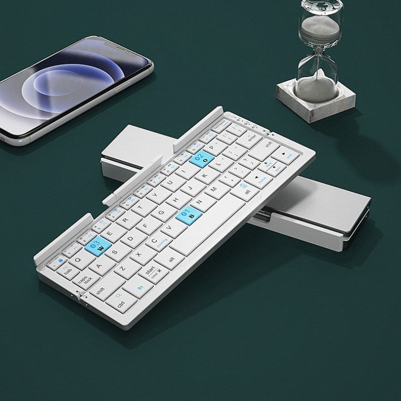 Foldable keyboard on a dark surface with a smartphone and hourglass in the background